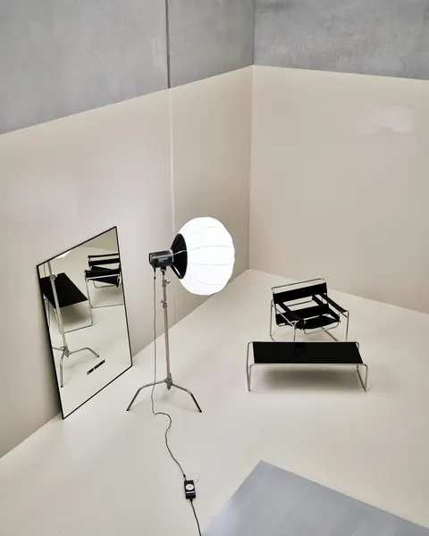 Projecteur à boule et chaise de cuir dans le studio blanc, un grand miroir posé contre le mur