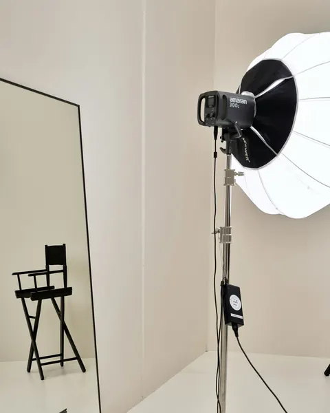 Boîte à lumière ronde sur pied et chaise de plateau devant un miroir