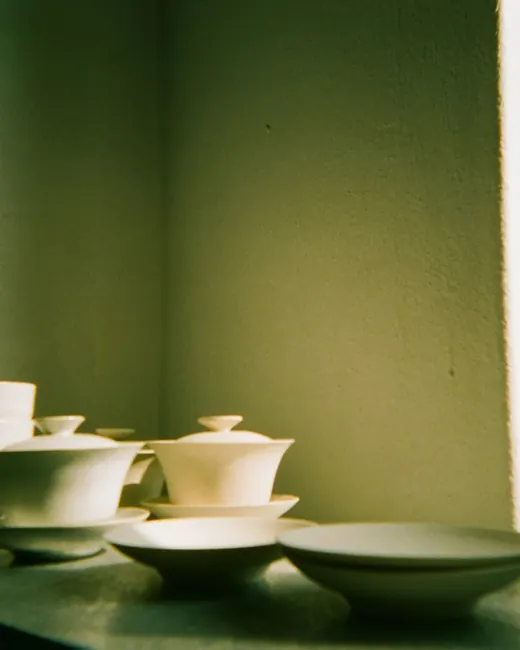 Bols et tasses de céramique blanche dans la lumière verte d’une pièce